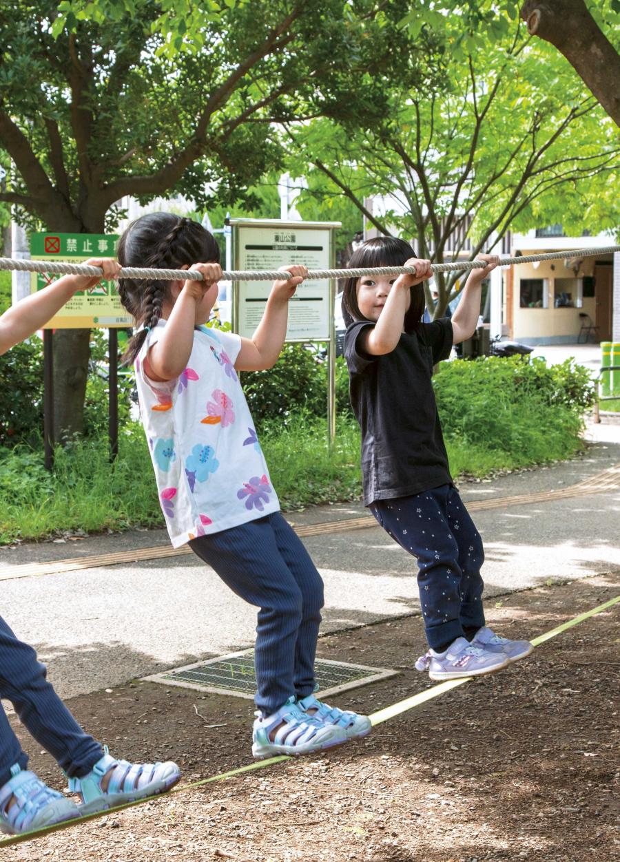 モンキーロープにつかまって揺らしたり移動したりして楽しむ子ども