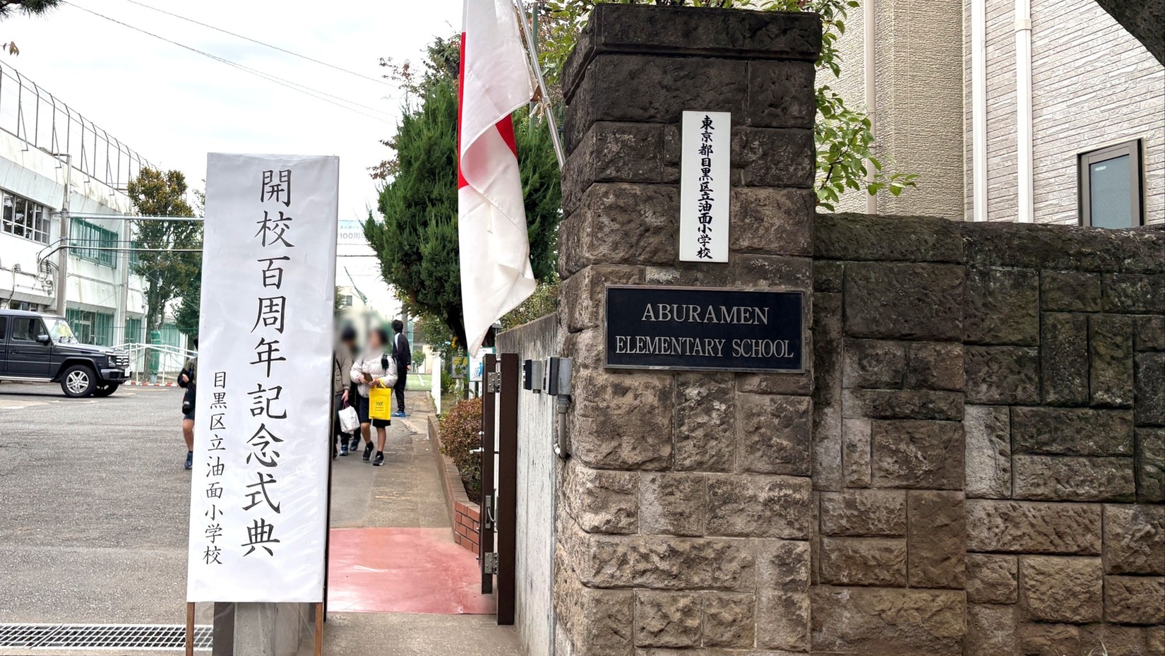 「開校100周年記念式典」の看板が立つ油面小学校 校門。