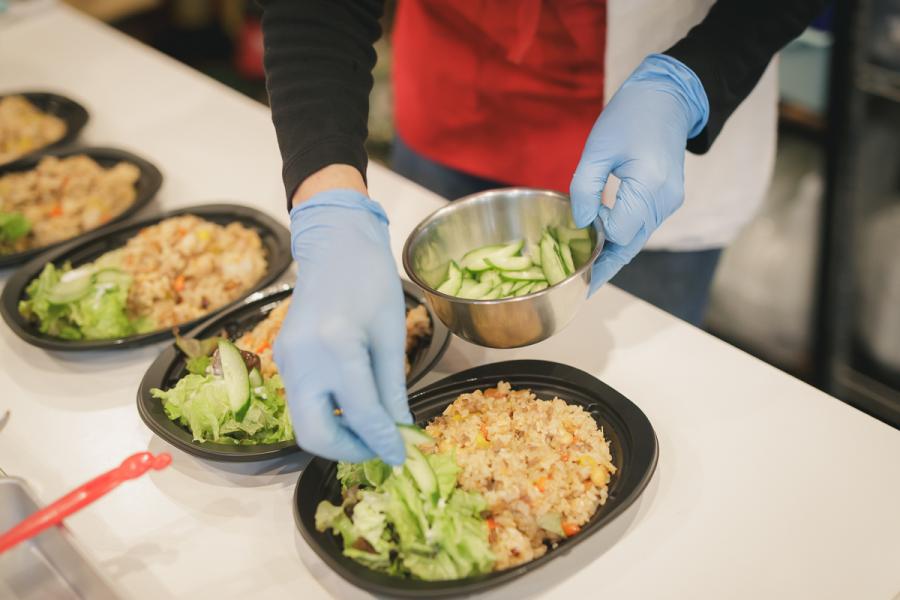 ナシゴレンの調理写真1。野菜を弁当につめているところ。
