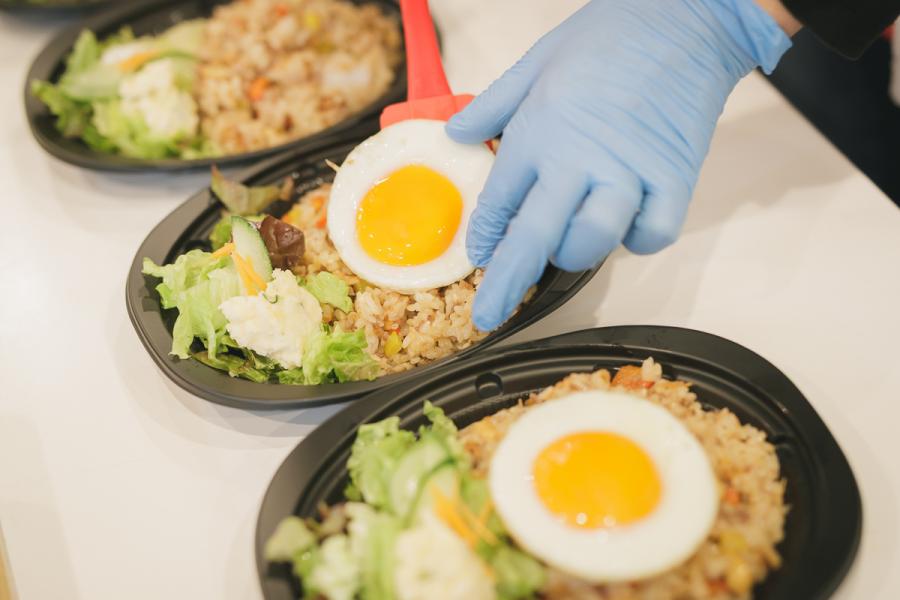 ナシゴレンの調理写真2。目玉焼きをご飯にのせているところ。