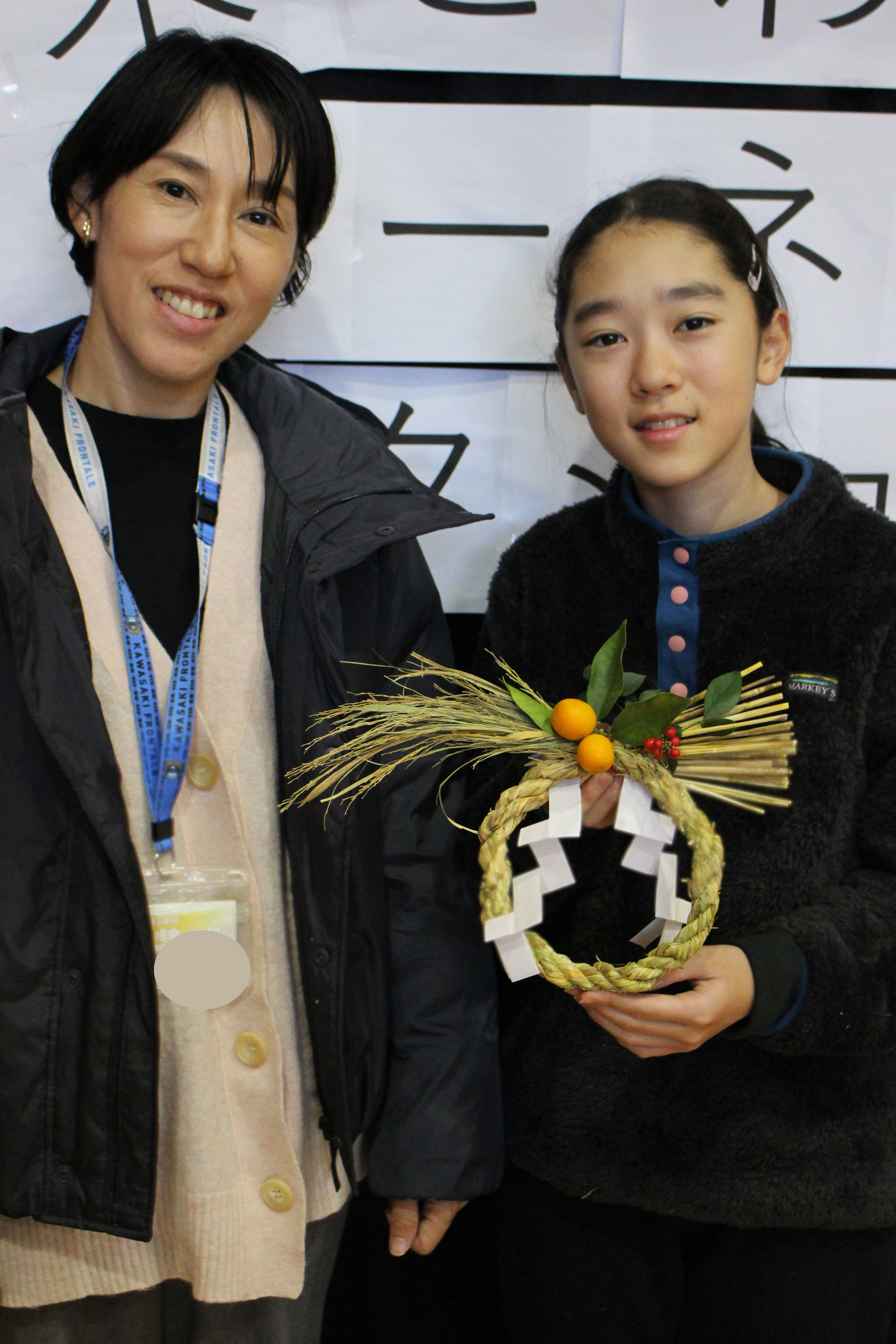 完成したしめかざりを持つ親子の写真