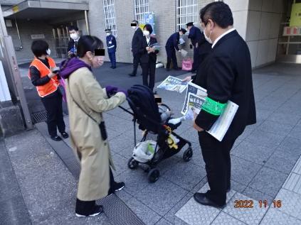 区職員が、めぐろ区報（特殊詐欺被害を防ぐ）を配布し、迷惑電話防止機器の紹介している様子の写真