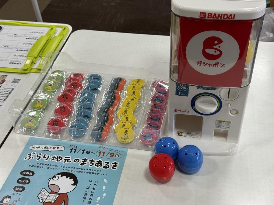 ゴールイベント会場の景品（缶バッチ）と景品を引くガシャポン